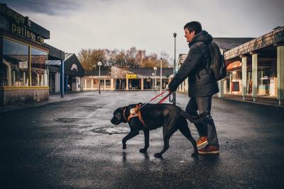 Homme avec son chien d'aveugle dans une rue déserte