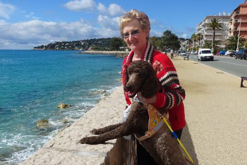 Suzanne est avec son chien guide, magic, un caniche royal au bord de la mer