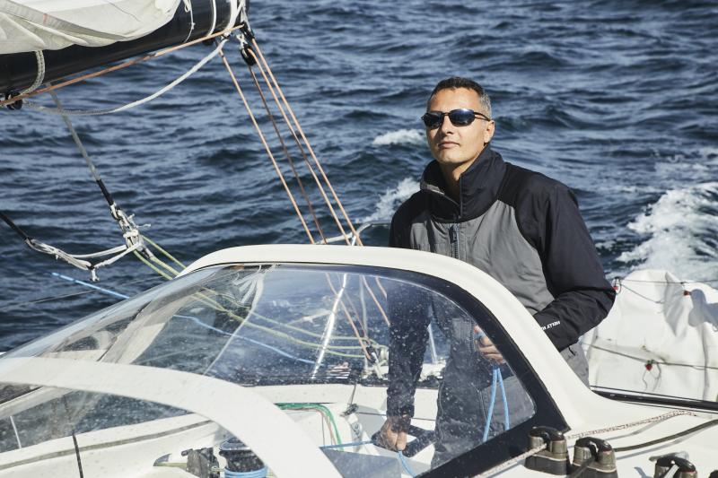 Un homme debout sur son voilier avec des lunettes de soleil