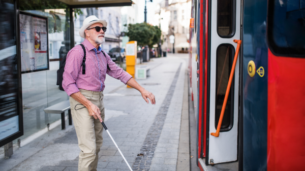 Un homme âgé avec une canne tente de rentrer dans un bus