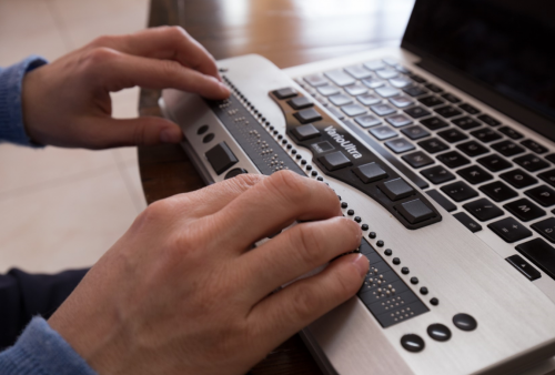 un homme tape sur une machine avec un langage braille qui écrit sur l'ordinateur
