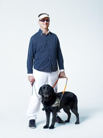 Un homme avec une casquette blanche tient son chien d'aveugle 