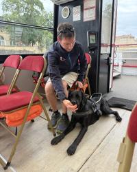 Un professionnel (moniteur ou éducateur) se trouve sur le bateau assis avec un chien guide en éducation durant un exercice.