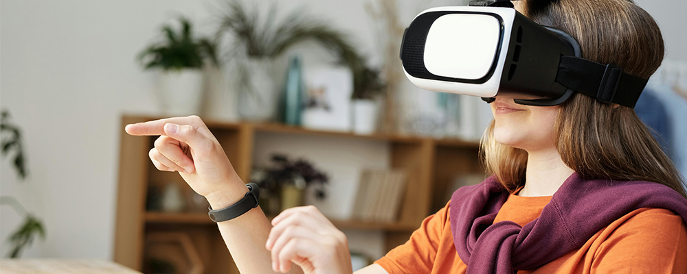 Une jeune fille porte un casque de réalité virtuelle sur le visage et touche, avec ses mains, des éléments virtuels, invisibles sans le casque.