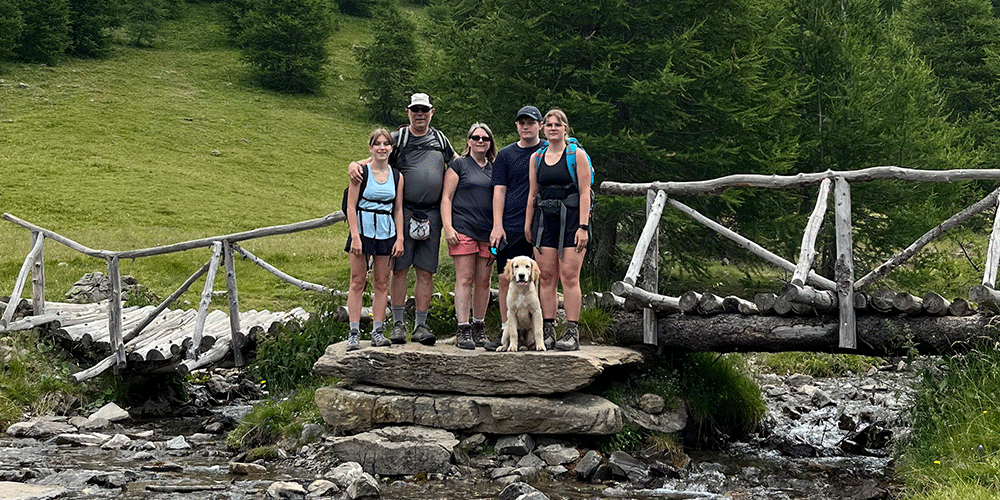 Une photo d'Éric de sa femme et leurs trois enfants avec en premier plan Uron, un labrador sable qui est  un chien guide en éducation.